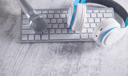 Microphone, keyboard and headphones on a white desk.の写真素材