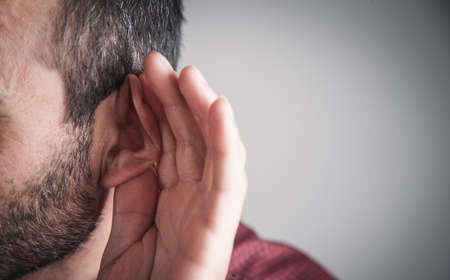 Caucasian man hold hand near ear. Trying to hear a gossipの写真素材