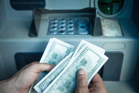 Man holding dollars withdrawn from ATM.