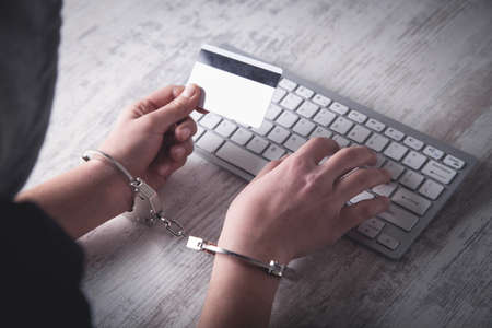 Hands in handcuffs typing on keyboard. Cyber Crime Conceptの写真素材