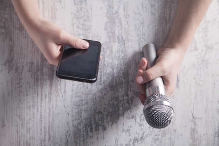 Journalist holding microphone and using smartphone.