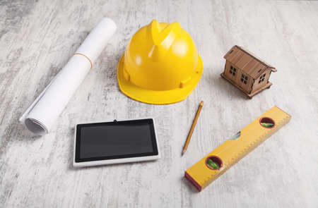 Wooden house model with a helmet and tablet.