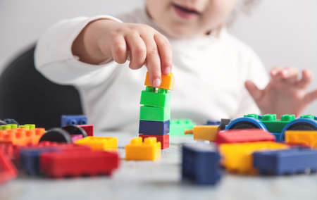 Little girl playing with colorful construction plastic blocks.