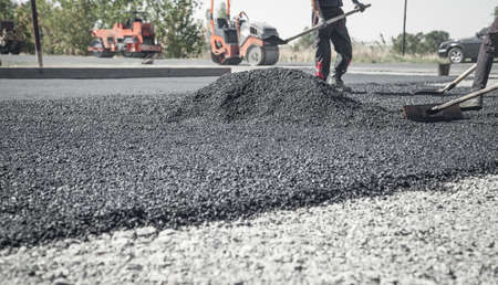 Workers arranging asphalt. Road construction. Industry