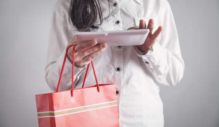 Business girl using tablet and holding shopping bag.