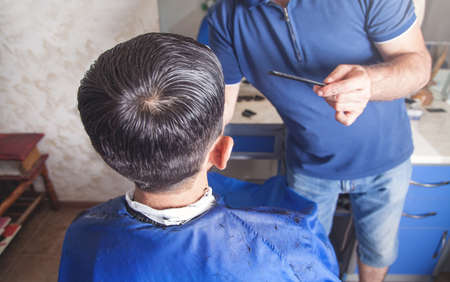 Barber making stylish haircut with in beauty salon.