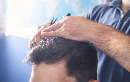 Barber making stylish haircut with in beauty salon.の写真素材