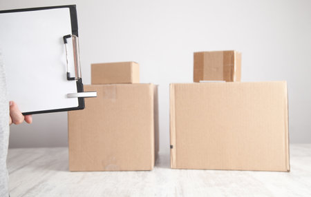 Man holding clipboard and pen. Cardboard boxes on the desk. Products, Commerce, Retail, Delivery