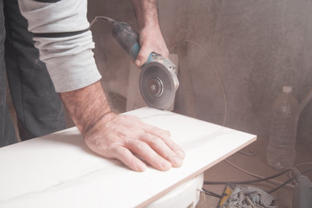 Worker cutting a tile with a grinder.