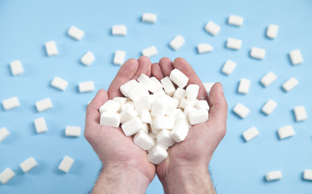 Male hands holding sugar cubes on the blue background.の写真素材