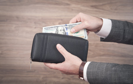 Businessman holding dollars with wallet.