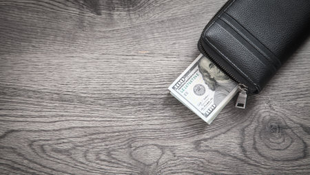 Black leather wallet and dollar banknotes.