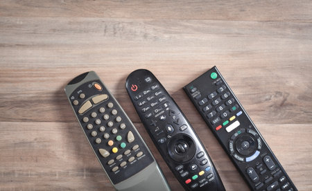 TV remote controllers on the wooden background.の写真素材