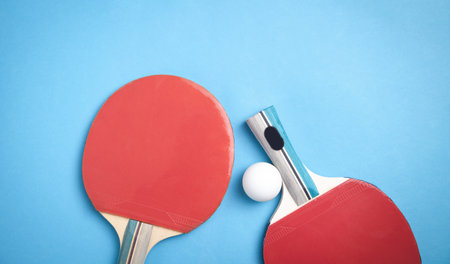 Table tennis rackets and a white plastic ball on the blue background.の写真素材