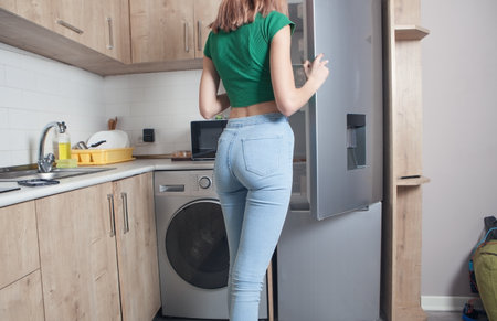 Woman opening refrigerator door at home.の写真素材