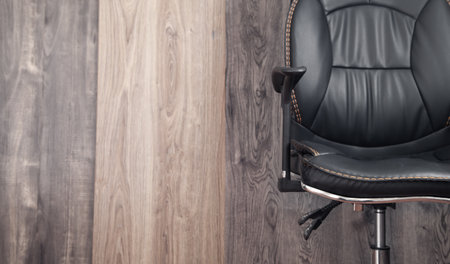 Black leather office chair in wooden background.の写真素材
