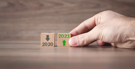 Male hand showing 2020 and 2021 on wooden cubes.