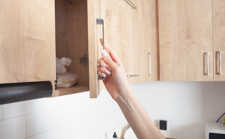 Caucasian woman opens the kitchen door furniture.
