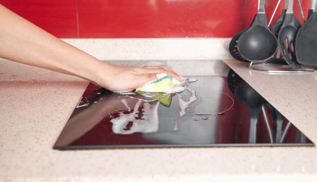 Woman washing modern electric stove in kitchen.の写真素材