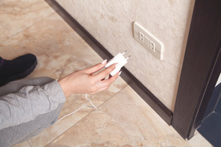 Woman hand with a charger in socket.の写真素材