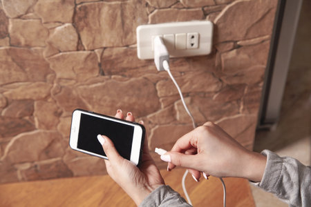 Woman connecting charger cable to mobile phone.の写真素材
