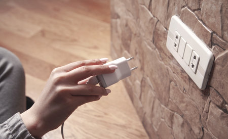Woman hand with a charger in socket.
