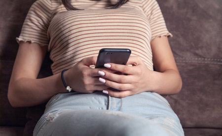 Woman using mobile phone while sitting on a couch at home.
