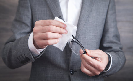 Businessman cleaning eyeglasses with wet wipe.の写真素材