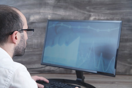 Businessman working with analytics sitting at the working place with computer. Graphs and charts on...
