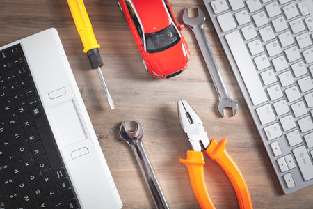 Toy car, wrench, screwdriver, pliers and computer keyboard.