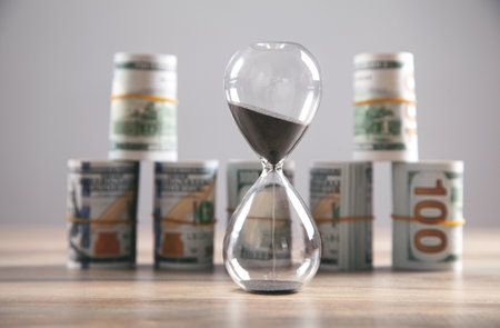 Hourglass and money on the desk. time is money