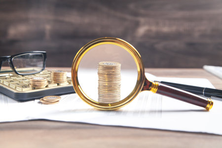 Magnifying glass, coins, eyeglasses, calculator, pen on financial documents. business. Financeの写真素材