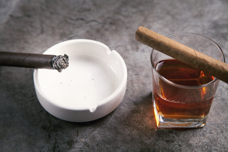 Glass of whiskey, ashtray and cigars on the table.の写真素材