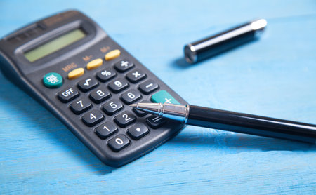 Calculator and pen on the blue background.の写真素材
