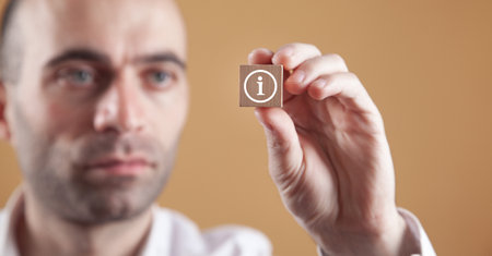Man showing information symbol on wooden cube.