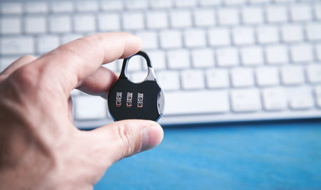 Hand holding padlock over computer keyboard. Internet and computer security