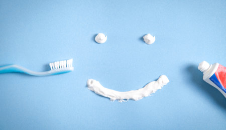 Toothbrush and toothpaste on the blue background. smiling face