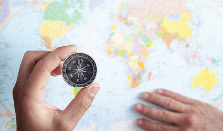 Male hand showing compass on the world map background.