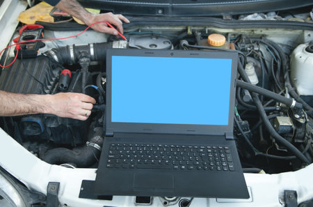 Mechanic with a multimeter testing car engine. laptop on car engine. car service. diagnostic car engineの写真素材