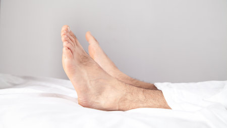 Male feet on the bed in the morning.