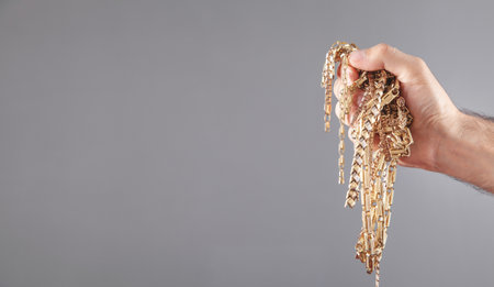 Male hand holding gold jewelry.