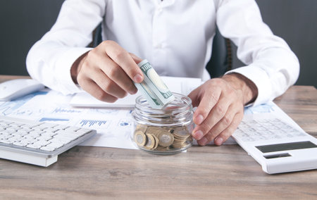 Businessman putting money in glass bank. saving money