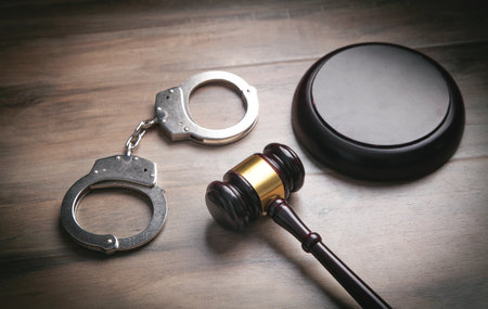 Metal handcuffs and judge gavel on the wooden background.の写真素材