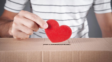 Male hand putting red heart in box.の写真素材