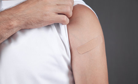 Caucasian man shows his shoulder with a bandage after vaccination.