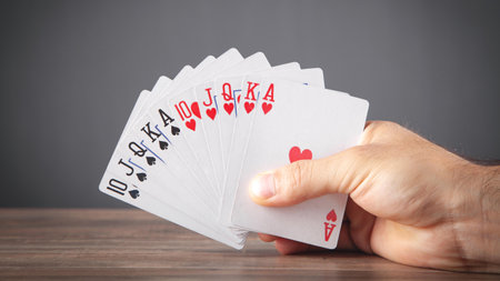 Male hand holding playing cards.