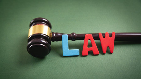 Word Law and judge gavel on green background.