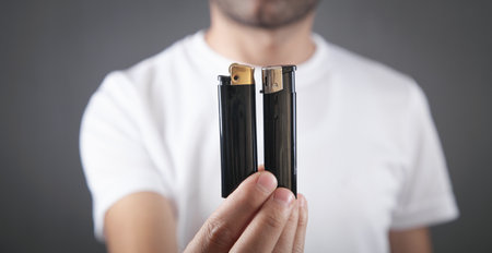 Male hand holding two black lighter.の写真素材
