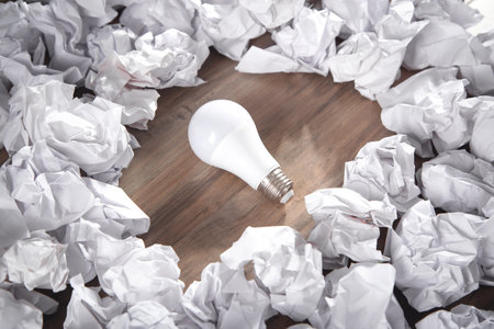Light bulb and crumpled papers on the wooden background.の写真素材
