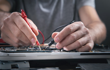 Technician hands checking motherboard with multimeter.の写真素材